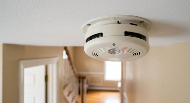 Smoke detector installed on a ceiling in a residential hallway